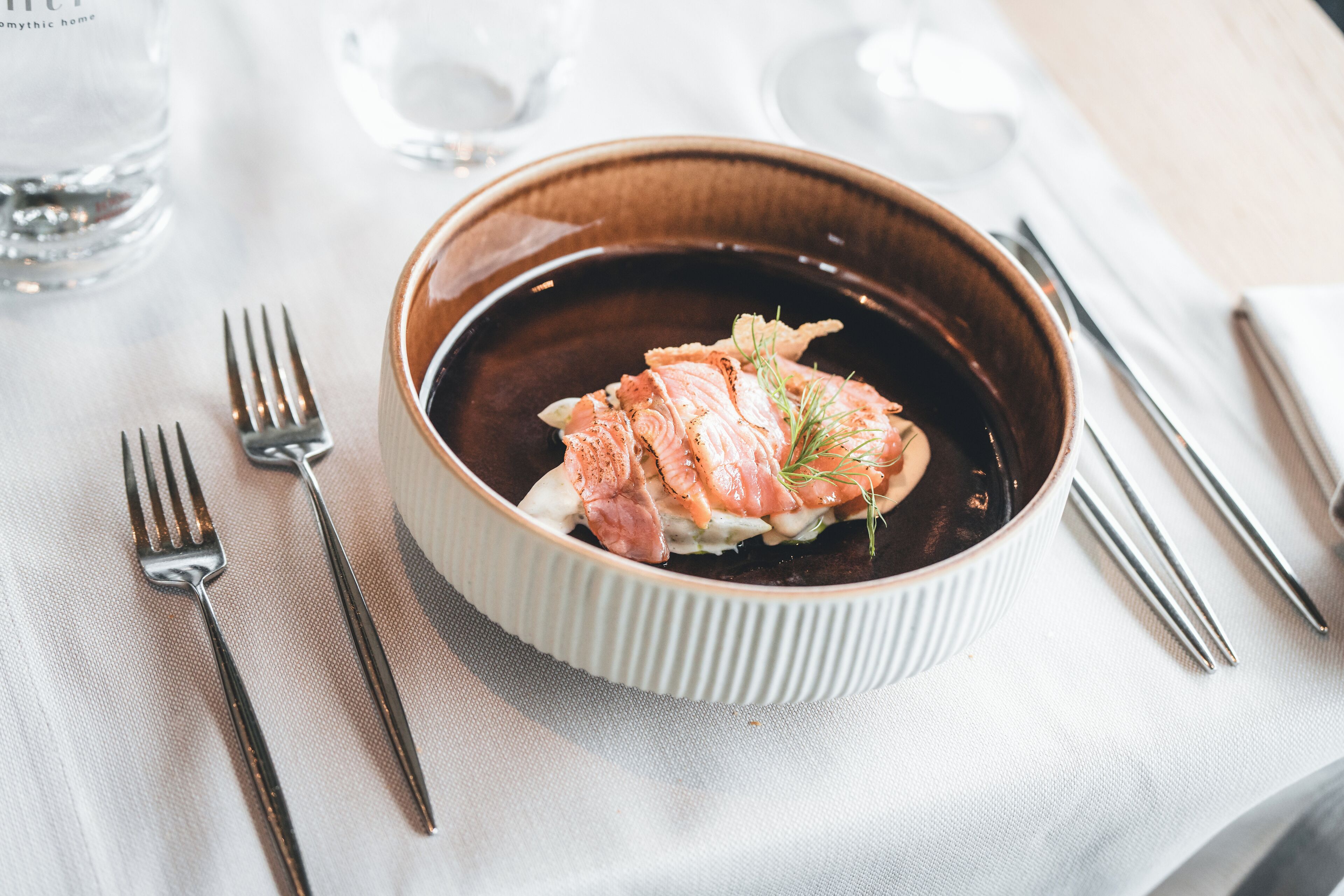 A bowl of food with a fork and knife on a table.