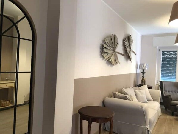Sala de estar com sofá, mesa redonda e obras de arte decorativas nas paredes.