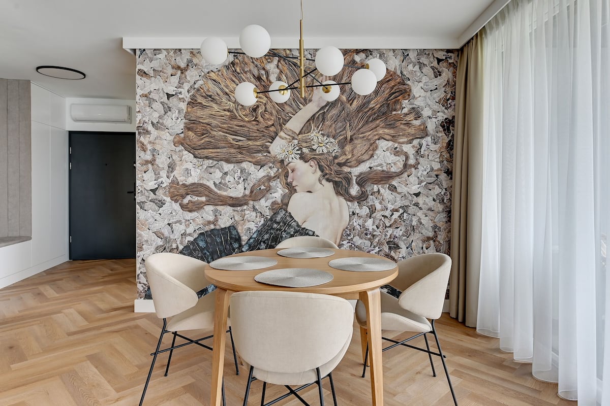 A dining area with a round table, four chairs, and a wall mural.