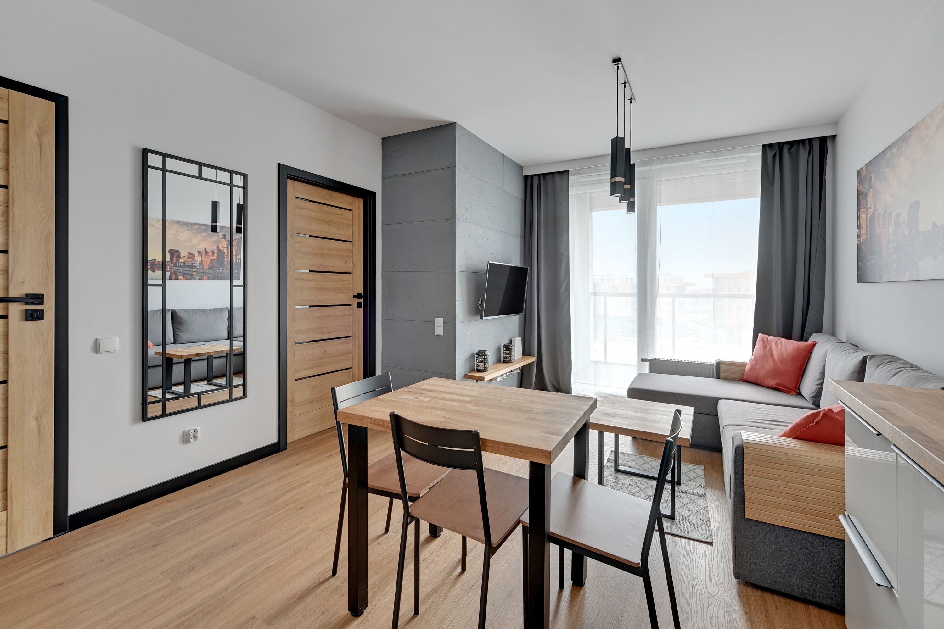 Un apartamento moderno con zona de comedor, sofá, televisor y un cuadro de la ciudad.
