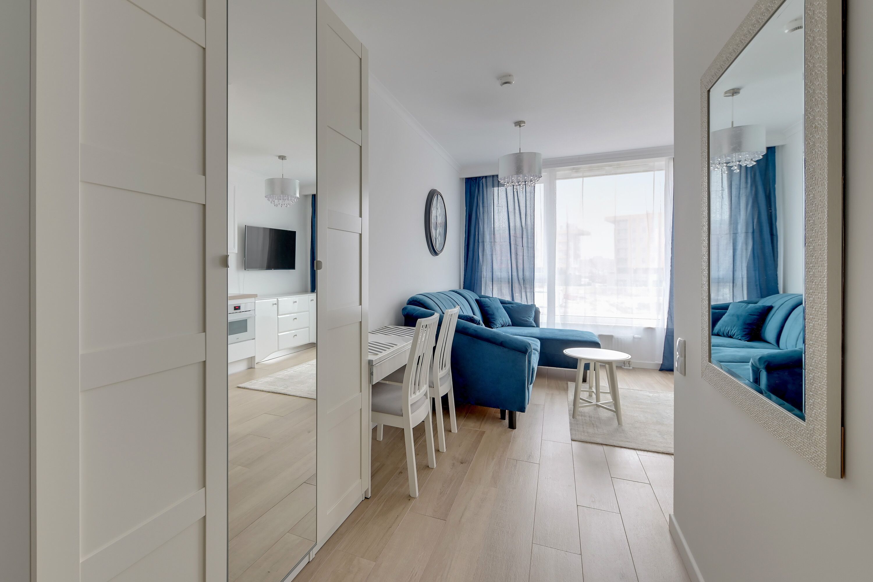 Un salon moderne comprenant un ensemble de canapés, une table à manger avec des chaises et un téléviseur fixé au mur.
