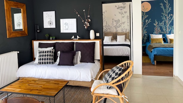 A modern bedroom with a large bed, a wooden coffee table, and a wicker chair. - HOUSE GARDEN BEACHES WALKS (Saint-Nazaire)