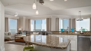 Eine moderne Küche mit Granitarbeitsplatte, Edelstahlgeräten und einer Sitzecke inklusive Sofa und Stühlen.