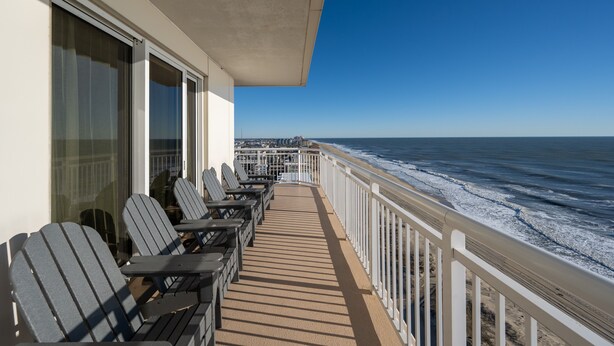 Ein Balkon mit Stühlen und Blick auf das Meer.