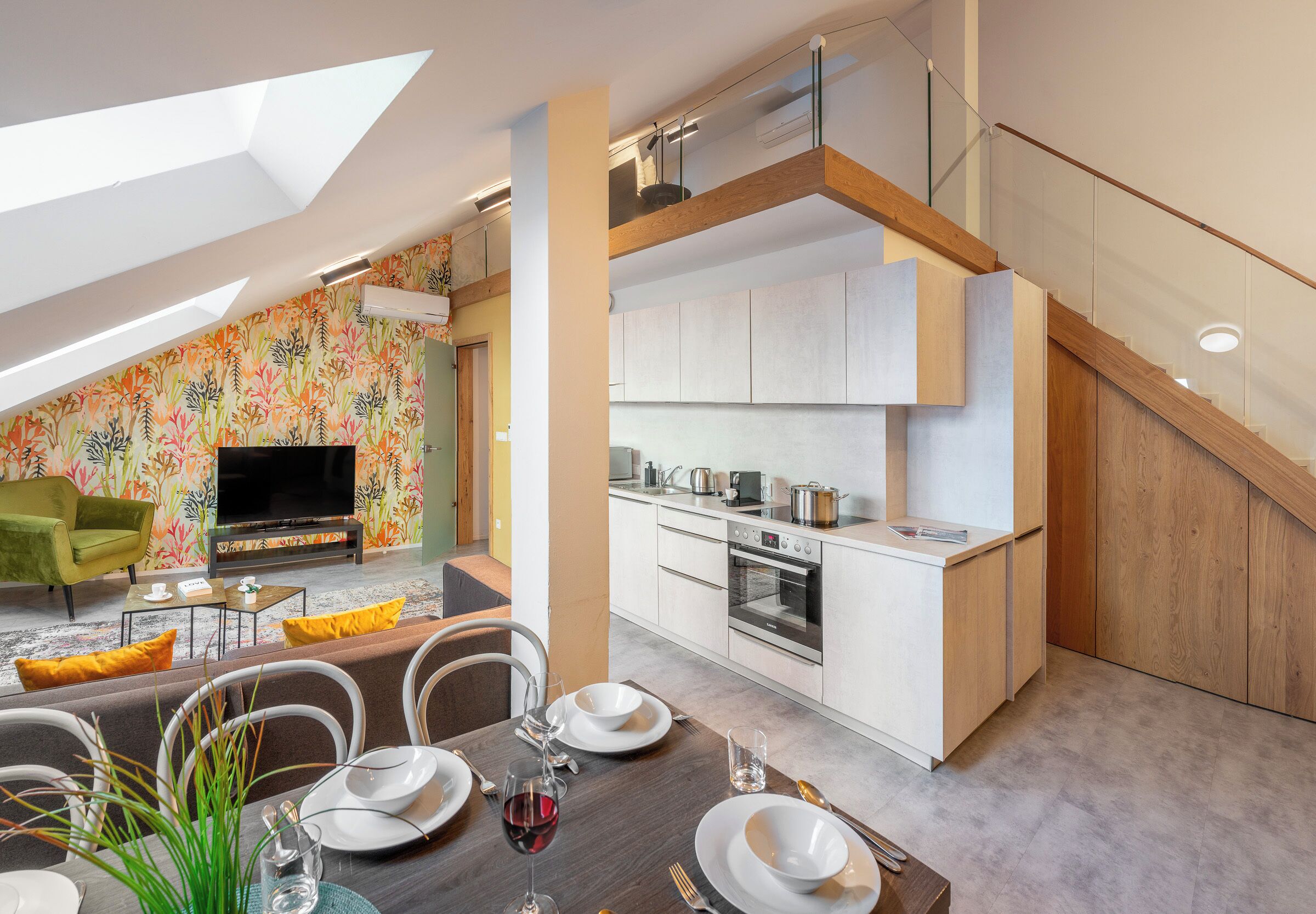 A modern kitchen with white cabinets and a wooden staircase.