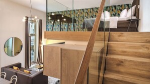 A modern interior with a wooden staircase, a mirrored wall, and a bed with a tropical leaf-patterned headboard. - VN48 Suites by Adrez Living (Prague)