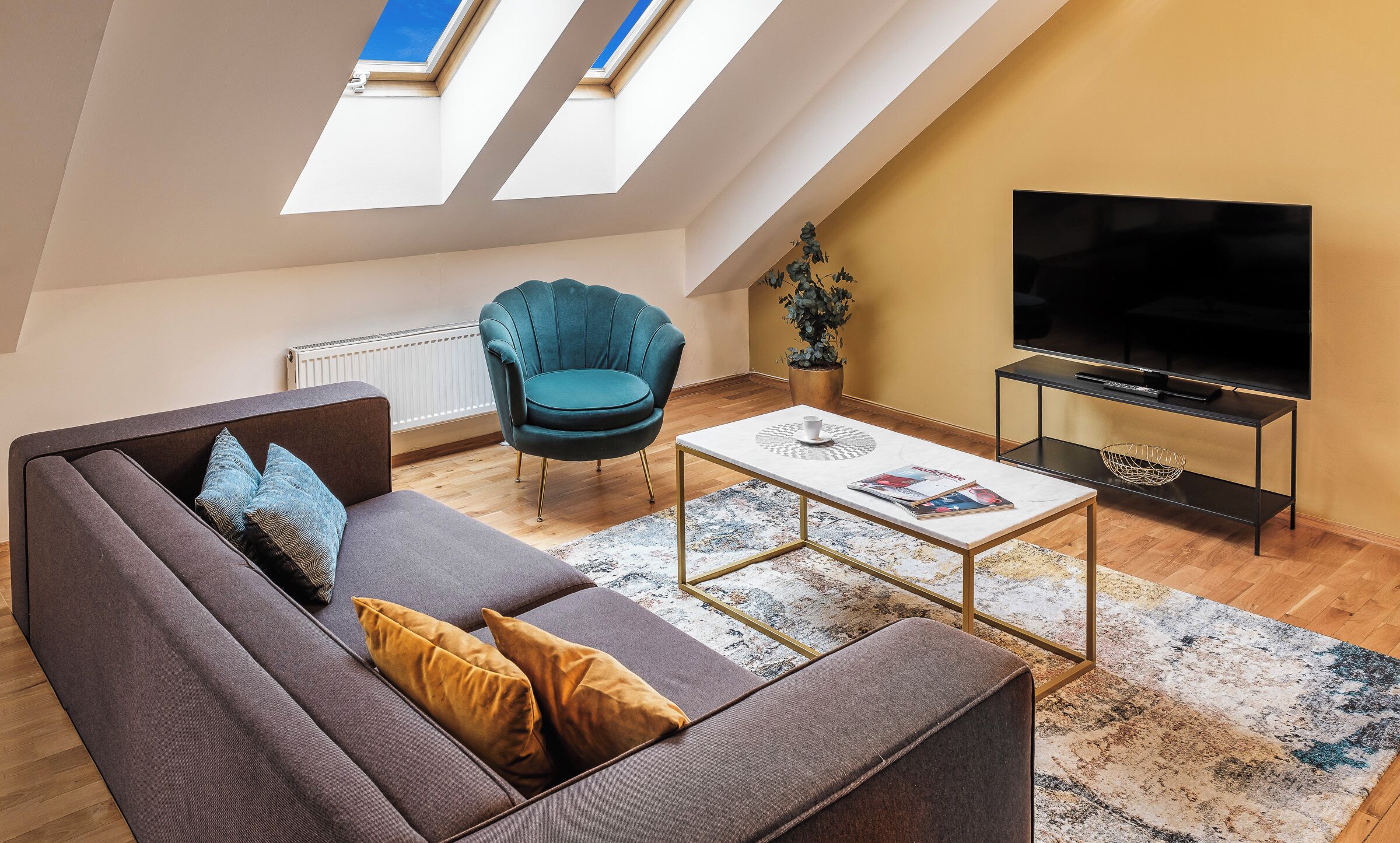 Una sala de estar moderna con sofá, sillón, mesa de centro y televisor.
