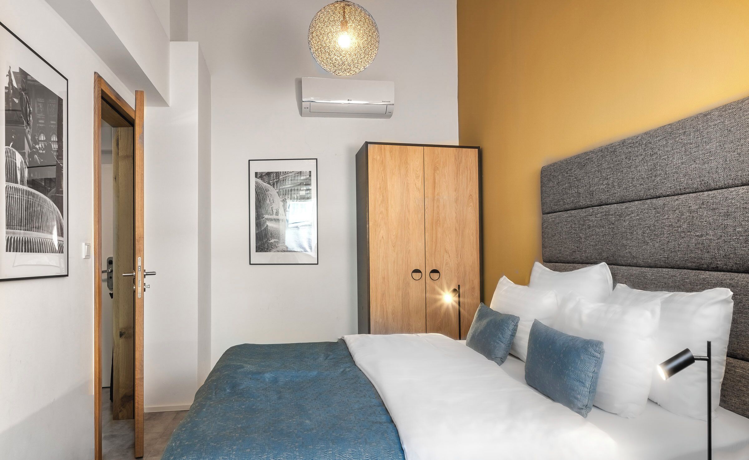 Un dormitorio con cama, armario, aire acondicionado en la pared y una puerta.