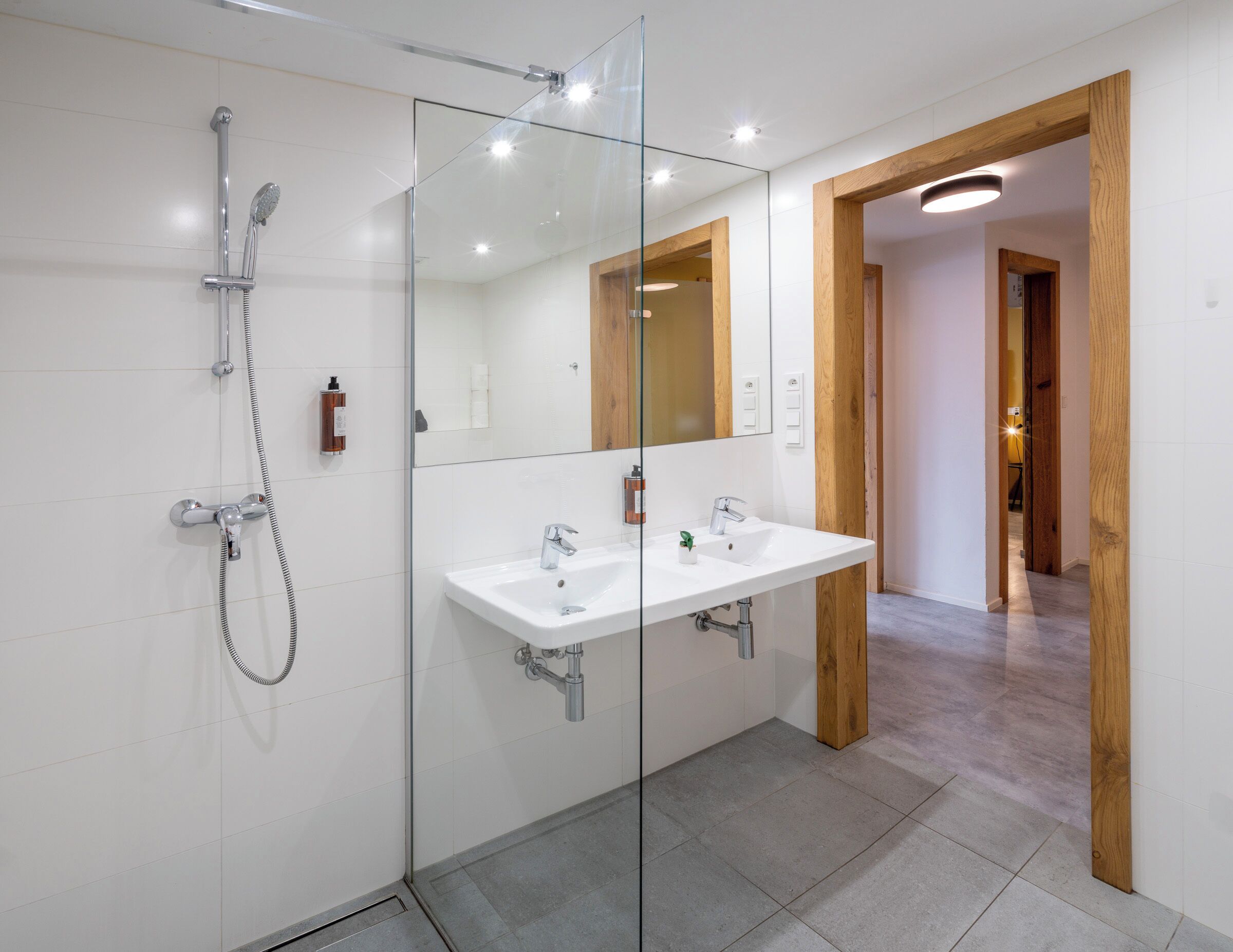 Een moderne badkamer met een douchecabine van glas, een witte wastafel en een grote spiegel.