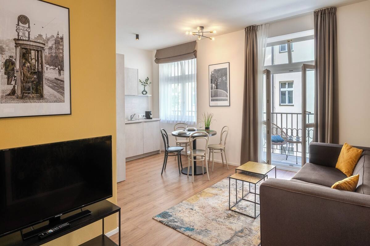 Uma sala de estar moderna com um sofá, uma televisão e uma área de jantar com cadeiras e uma mesa.