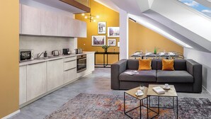 A modern kitchen with a built-in oven and microwave, a dining area with a table set for four, and a cozy seating area with a sofa and coffee table. - VN48 Suites by Adrez Living (Prague)