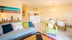 A modern living room with a sofa, a dining area with a table and chairs, and a kitchen in the background. - LE FOCH AP4244 By Riviera Holiday Homes (Niza)