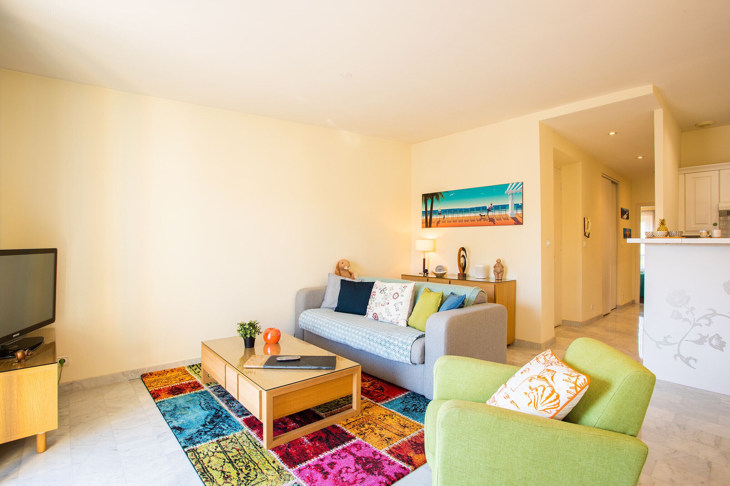 Un salon moderne avec un canapé, un fauteuil vert, une table basse et un téléviseur.