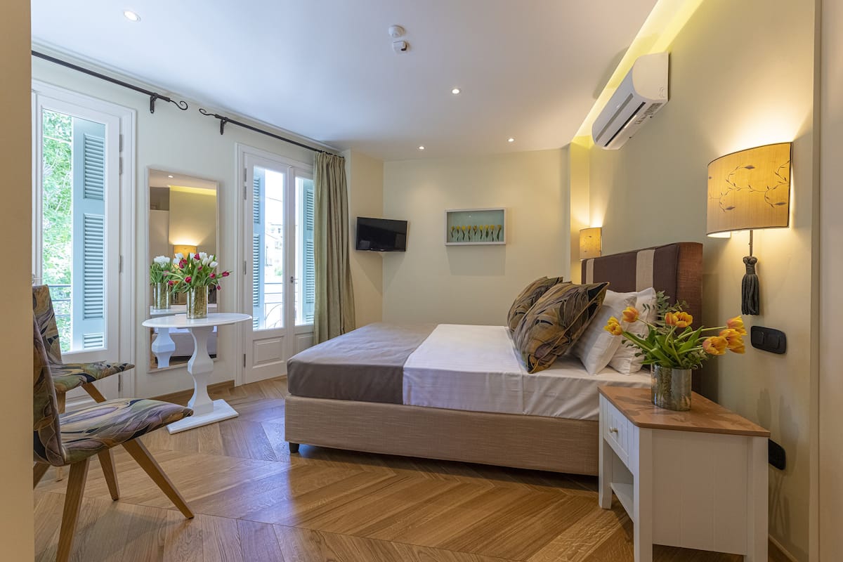 A bedroom with a bed, bedside table, chair, and a small table with flowers.