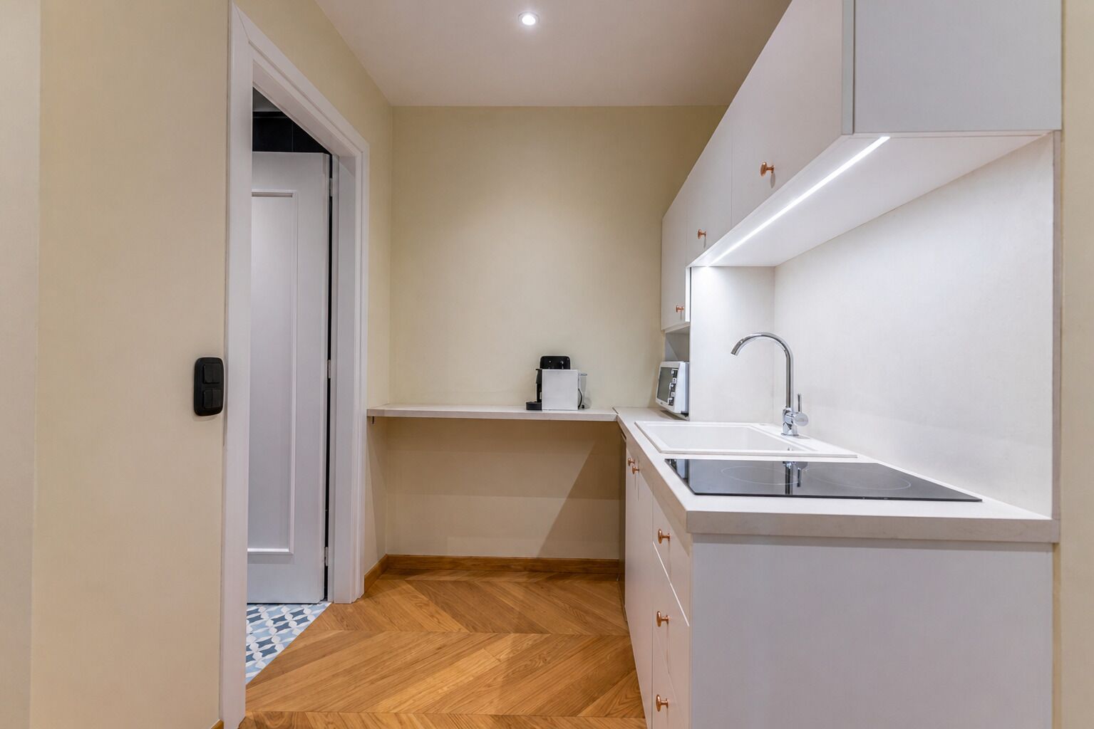 A compact kitchen with a sink, countertop, and a microwave.