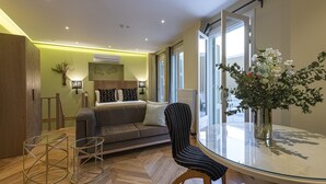 A modern living room with a sofa, a glass table, and a vase of flowers. - Ipelhome Plaka Boutique Apartments (Athens)