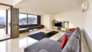 Ein modernes Wohnzimmer mit einer großen Sofagarnitur, einem Couchtisch und einem Flachbildfernseher.