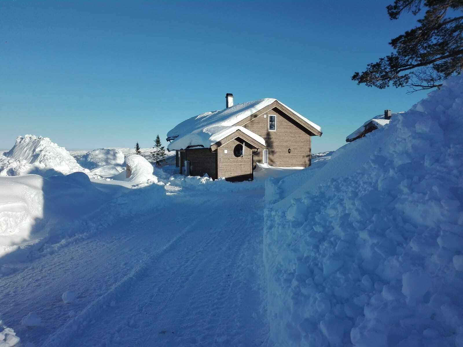 A wooden cabin surrounded by snow-covered terrain.