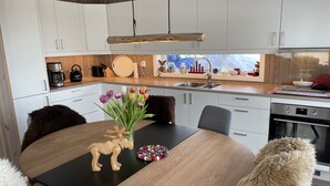 A modern kitchen with white cabinets, a wooden dining table, and a vase of tulips.