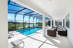 Un espacio al aire libre techado con piscina, asientos y vista a un lago.