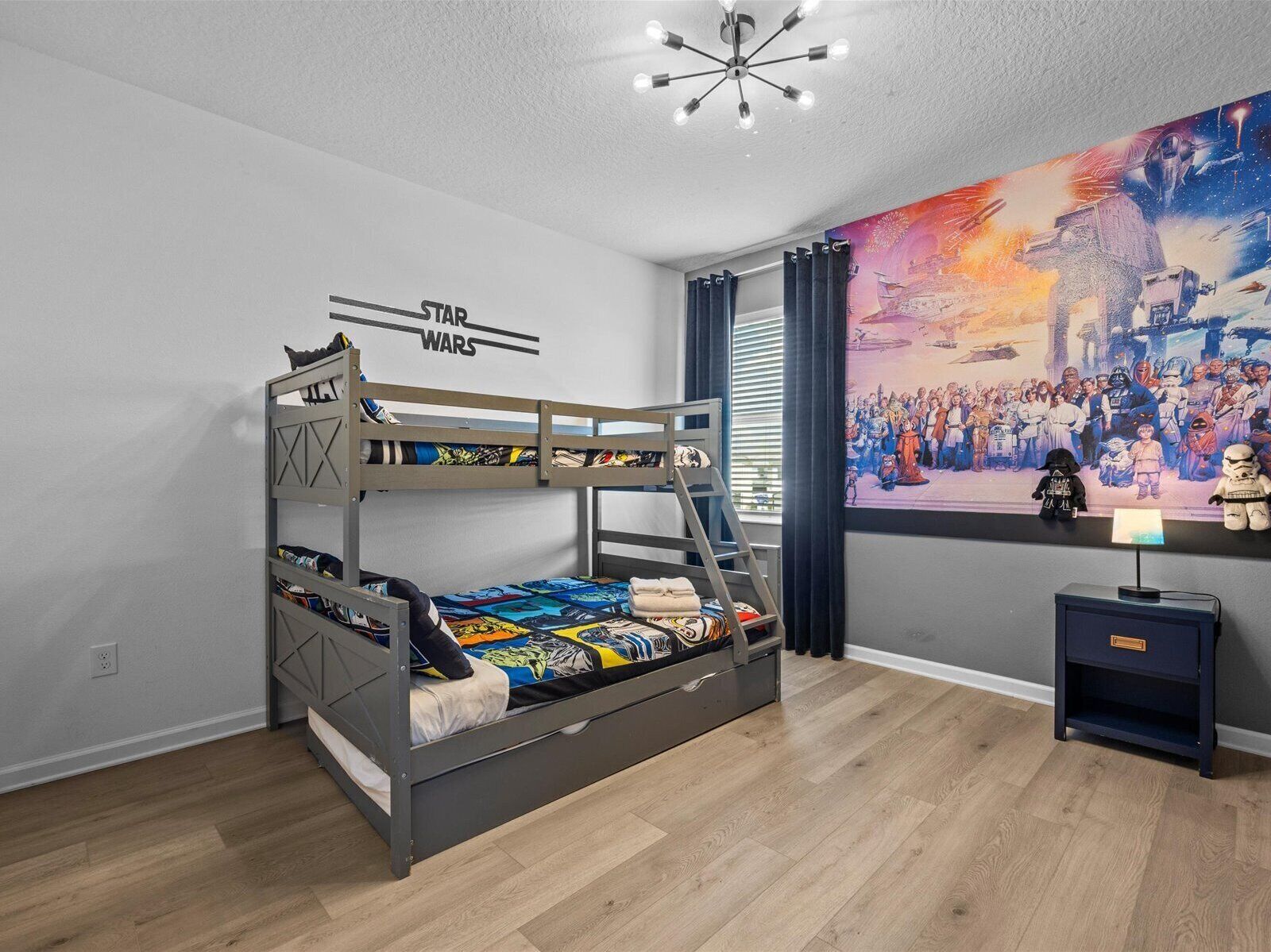 Una cama litera con decoración de Star Wars, un cartel de Star Wars y una figurita de Star Wars en un estante.