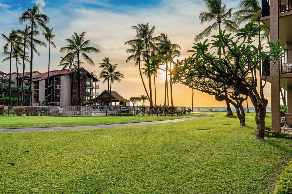 A hotel with a pool, palm trees, and a sunset view.