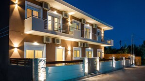 A modern two-story building with balconies, air conditioning units, and a well-lit facade. - Orea Homes (Parga)