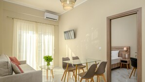 A modern living room with a glass dining table, a sofa, and a coffee table with a plant. - Orea Homes (Parga)