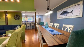 Zona pranzo con tavolo in legno, sedie bianche e runner decorato blu.