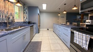 Una cucina moderna con un piano di lavoro in marmo, elettrodomestici in acciaio inossidabile e luci a sospensione.