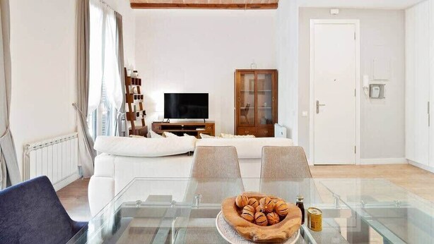 Un salon moderne avec une table à manger en verre, un canapé blanc et un téléviseur.