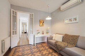 Un salon comprenant un canapé, une table basse, un luminaire suspendu et un climatiseur fixé au mur.