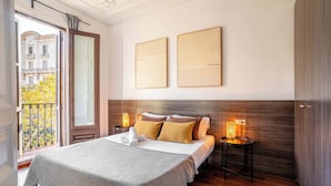 Une chambre d’hôtel avec un grand lit, deux lampes de chevet, une vue sur un balcon avec une balustrade et une fenêtre avec des rideaux.