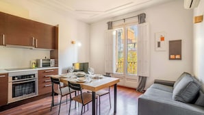 Une cuisine moderne avec des meubles en bois, une table à manger pour quatre personnes et un canapé gris.