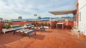 Une terrasse sur le toit, aménagée avec des chaises longues, une table et des plantes en pot.