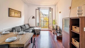 Un salon moderne comprenant un coin repas, un canapé, un téléviseur et une vue sur l’extérieur.