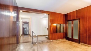 Un hall d’hôtel avec un comptoir d’accueil en bois, une porte en verre et un sol en marbre.