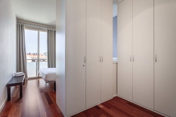 Een hotelkamer met een bed, een bankje en een grote kledingkast.