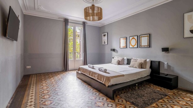 Un dormitorio con una cama grande, una mesita de noche pequeña, una alfombra y una lámpara en el techo.