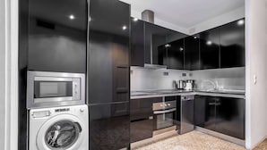 Una cocina compacta equipada con lavadora, microondas y horno.