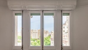 Une pièce dotée de trois grandes fenêtres, chacune ayant un cadre blanc et un élément décoratif vert en partie supérieure.