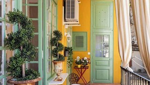 A narrow corridor with a tiled floor, green-framed windows, a white table, a bench, and a door. - Amazing 5Bd for 13 with terrace in Plaza Cataluña (Barcelona)