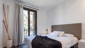 A modern hotel room with a large bed, a bedside table, a nightstand, and a window with curtains. - 3-bedroom penthouse with terrace in Eixample (Barcelona)