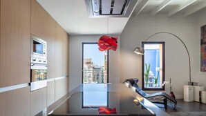 A modern kitchen with built-in appliances, a glass dining table, and a view of the city. - 3-bedroom penthouse with terrace in Eixample (Barcelona)