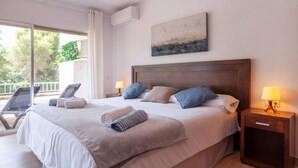 A hotel room with a large bed, two bedside lamps, a painting on the wall, and a balcony with a chair. - Golden Mile Apartment 150 m. to the beach (Marbella)