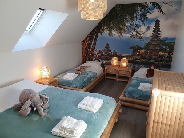 A room with two beds, a skylight, a mural of a pagoda, and a plush elephant toy.