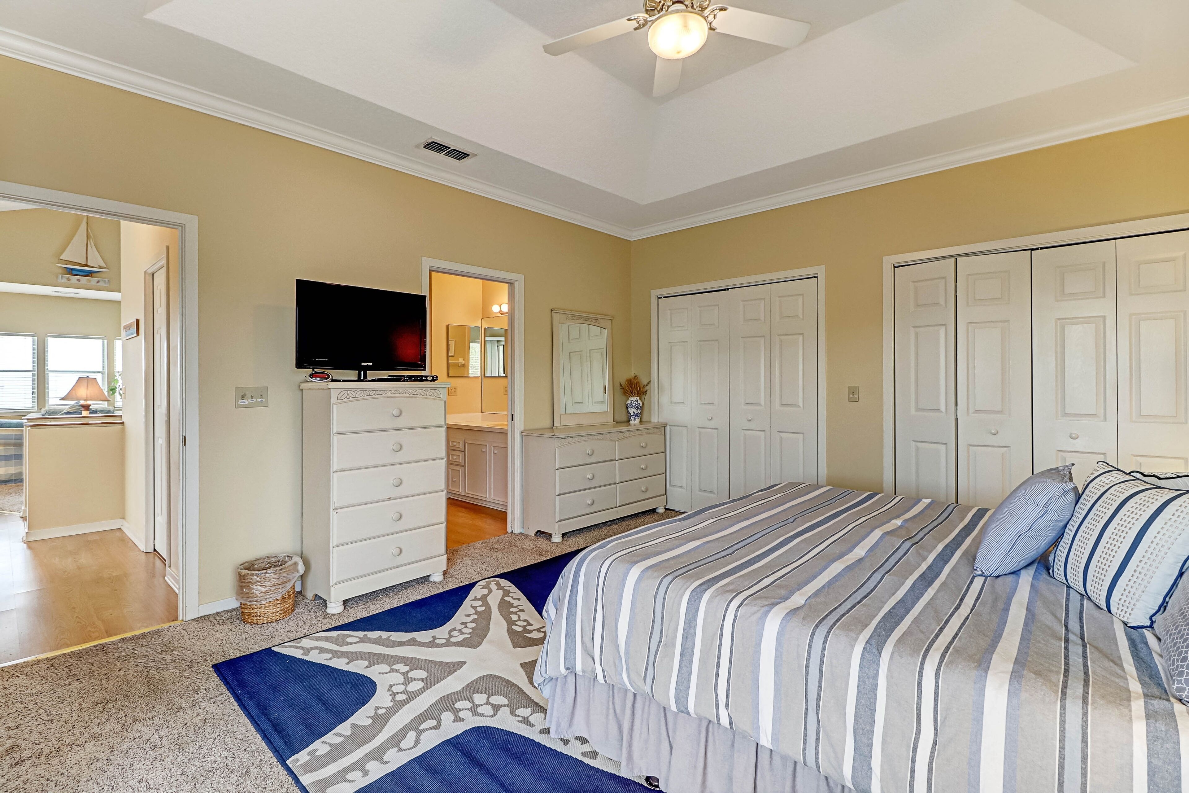 A bedroom with a large bed, a TV, a dresser, and a closet.