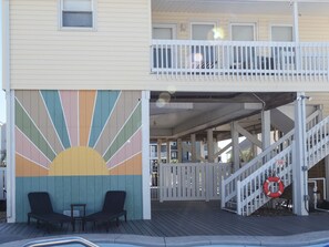 A building with a colorful mural, a covered outdoor area with a staircase, and a lifebuoy. - "Legasea" - 2nd Row Home w/ Private Pool, 4 Bedrooms / 3 Bathrooms (Holden Beach)
