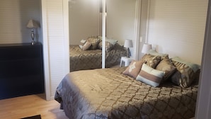 Un dormitorio con cama, mesitas de noche, lámparas y un espejo.