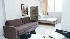A room with a brown sofa, a bed, a dining table with chairs, a glass partition, and a window with curtains. - Cozy and Comfy Central Athens Apt. (Athens)
